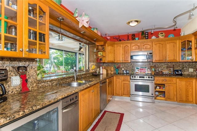 kitchen featuring dark stone counters, hanging light fixtures, sink, light tile patterned floors, and stainless steel appliances