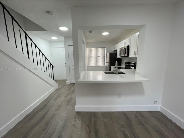 kitchen with white cabinets, sink, appliances with stainless steel finishes, dark hardwood / wood-style flooring, and kitchen peninsula