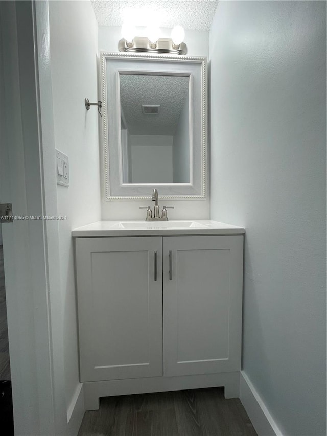 bathroom with hardwood / wood-style floors, vanity, and a textured ceiling