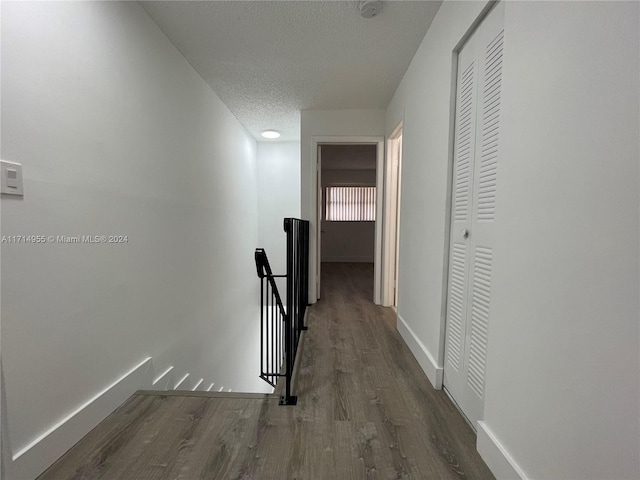 corridor with dark hardwood / wood-style floors and a textured ceiling