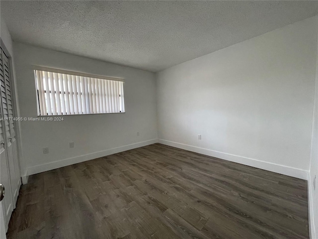 empty room featuring dark hardwood / wood-style floors and a textured ceiling