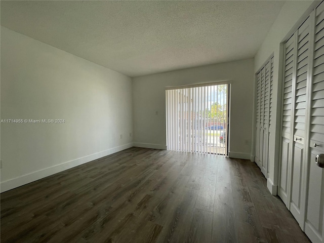 unfurnished bedroom featuring access to exterior, a textured ceiling, and dark hardwood / wood-style flooring