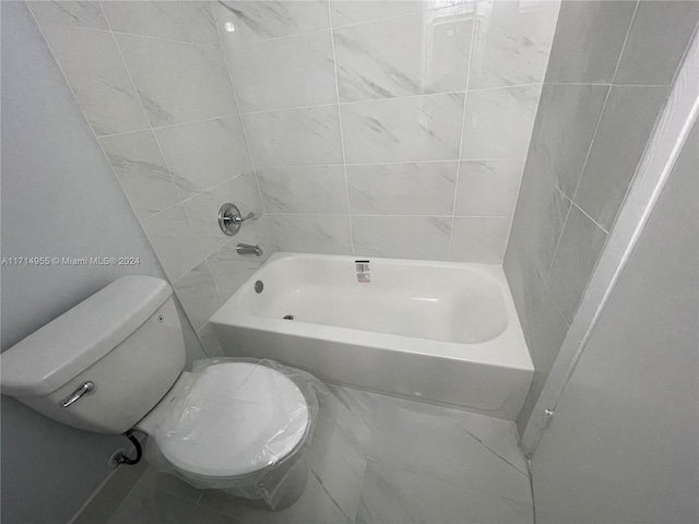 bathroom with toilet and tiled shower / bath