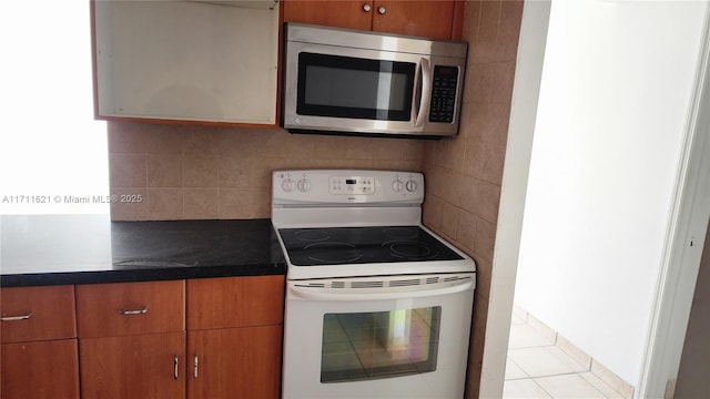 kitchen featuring tasteful backsplash, light tile patterned flooring, and white electric range oven