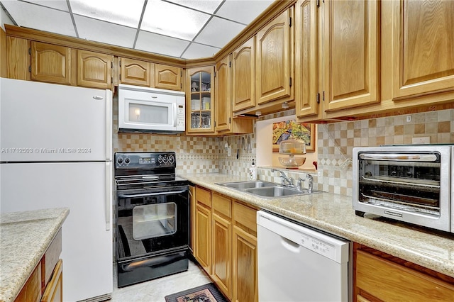 kitchen with light stone countertops, white appliances, sink, and tasteful backsplash