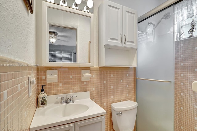 bathroom featuring vanity, toilet, an enclosed shower, and tile walls