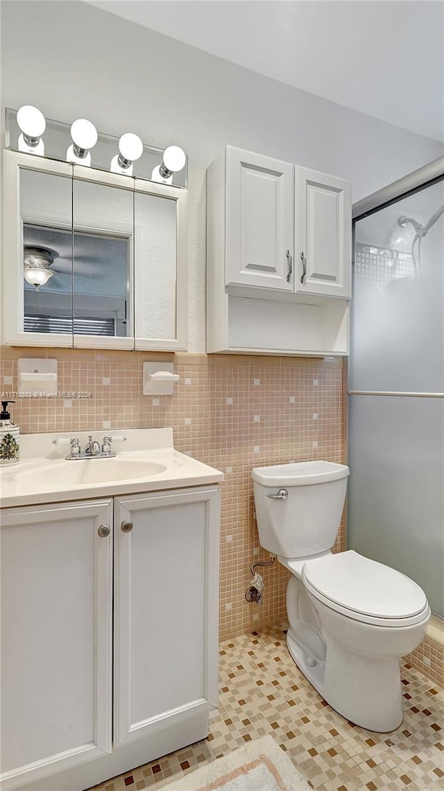 bathroom featuring tile patterned flooring, vanity, toilet, and tile walls