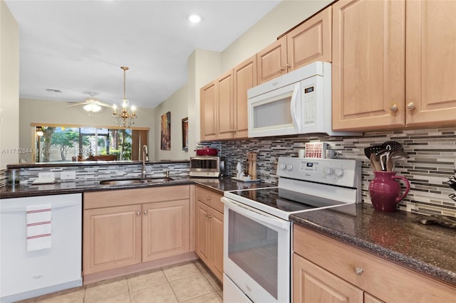 kitchen featuring sink, tasteful backsplash, dark stone countertops, pendant lighting, and white appliances