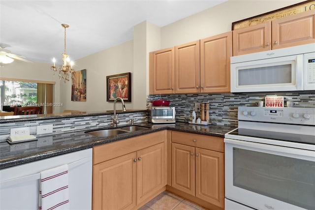 kitchen with light tile patterned flooring, white appliances, dark stone countertops, and sink