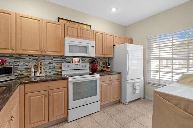 kitchen with backsplash, dark stone countertops, light tile patterned floors, and white appliances