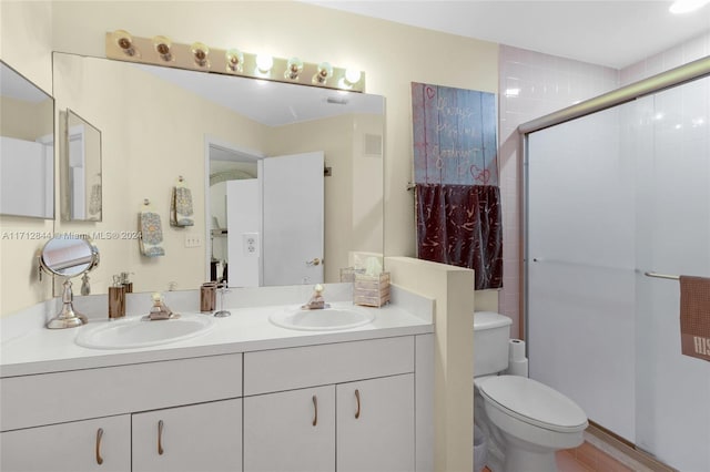 bathroom with vanity, a shower with shower door, and toilet