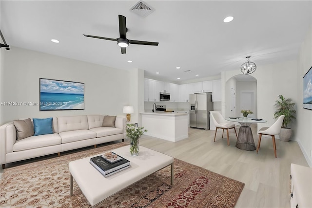 living room featuring light wood-type flooring and ceiling fan with notable chandelier