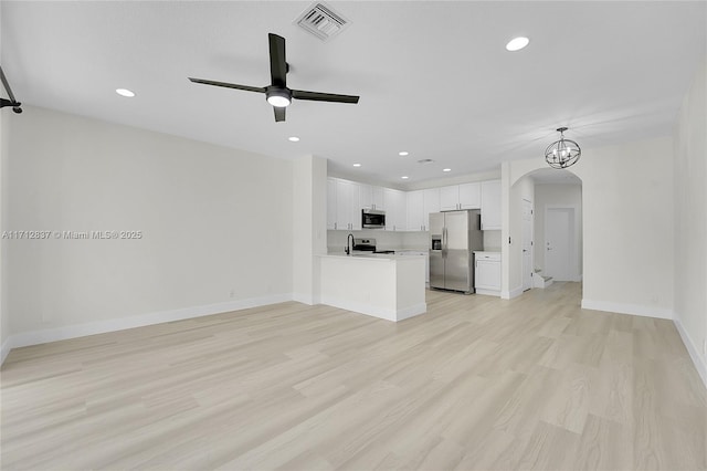 unfurnished living room with ceiling fan with notable chandelier and light hardwood / wood-style flooring