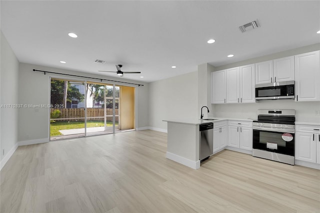 kitchen featuring white cabinets, ceiling fan, light wood-type flooring, kitchen peninsula, and stainless steel appliances