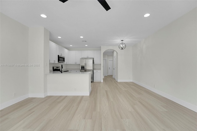 kitchen with white cabinetry, sink, stainless steel appliances, light hardwood / wood-style flooring, and kitchen peninsula