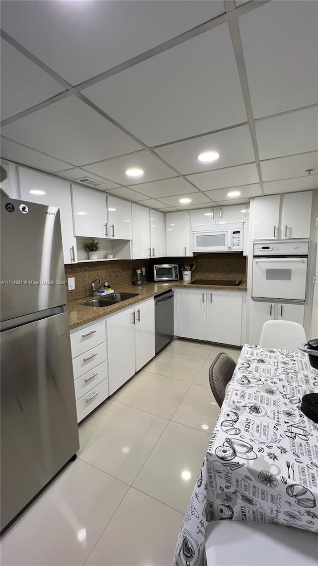 kitchen with white cabinets, appliances with stainless steel finishes, tasteful backsplash, and sink