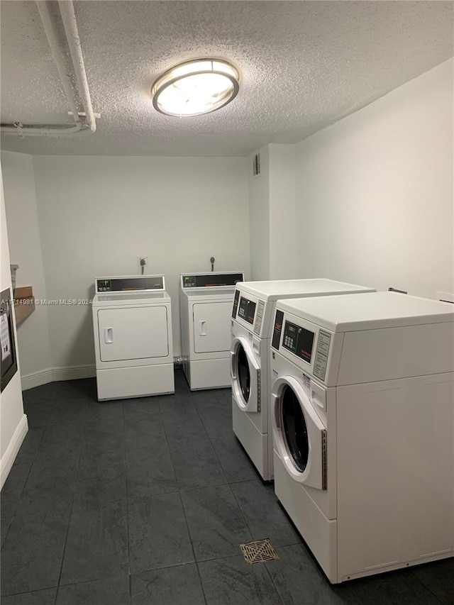 clothes washing area with washing machine and clothes dryer and a textured ceiling