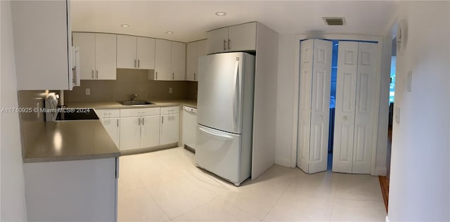 kitchen with stainless steel fridge, white dishwasher, sink, light tile patterned floors, and range