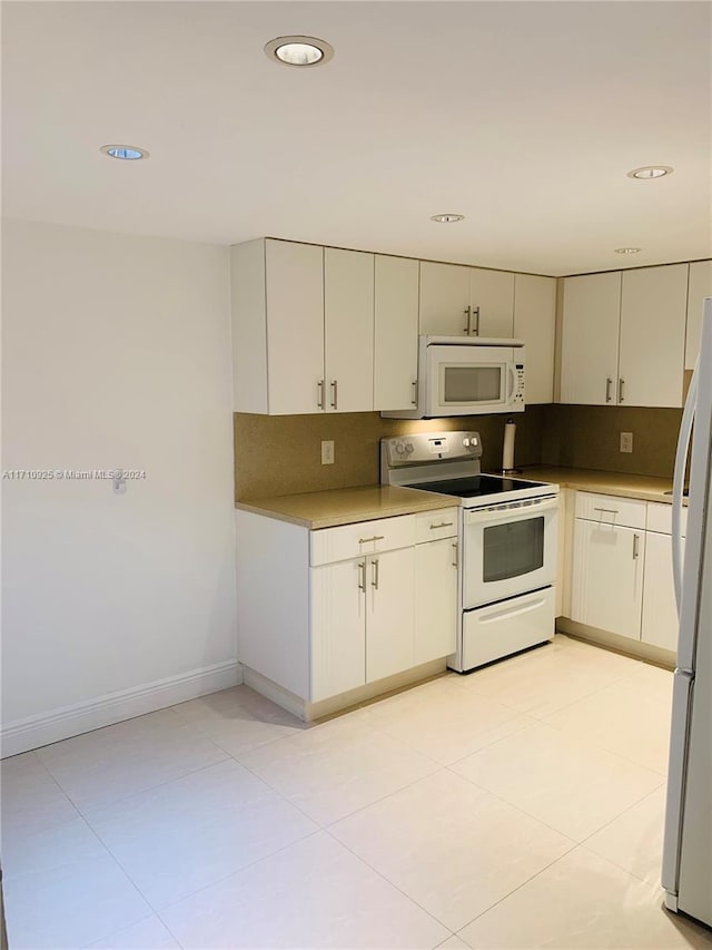 kitchen featuring decorative backsplash, white appliances, and white cabinets