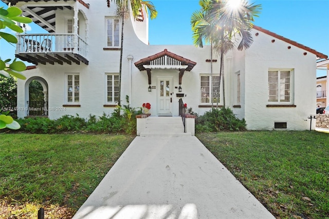 mediterranean / spanish-style home with a balcony and a front lawn