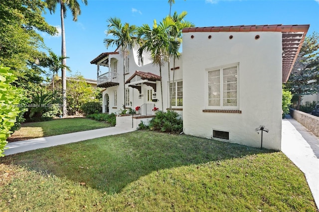 mediterranean / spanish-style home featuring a front yard and a balcony