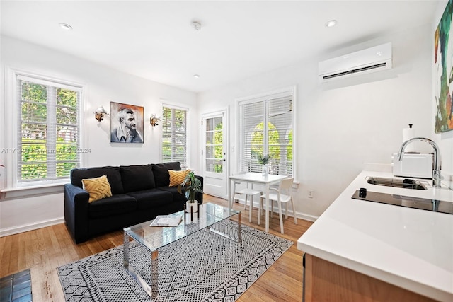 living room with plenty of natural light, sink, light hardwood / wood-style floors, and a wall mounted air conditioner