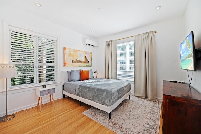 bedroom featuring light wood-type flooring and a wall unit AC