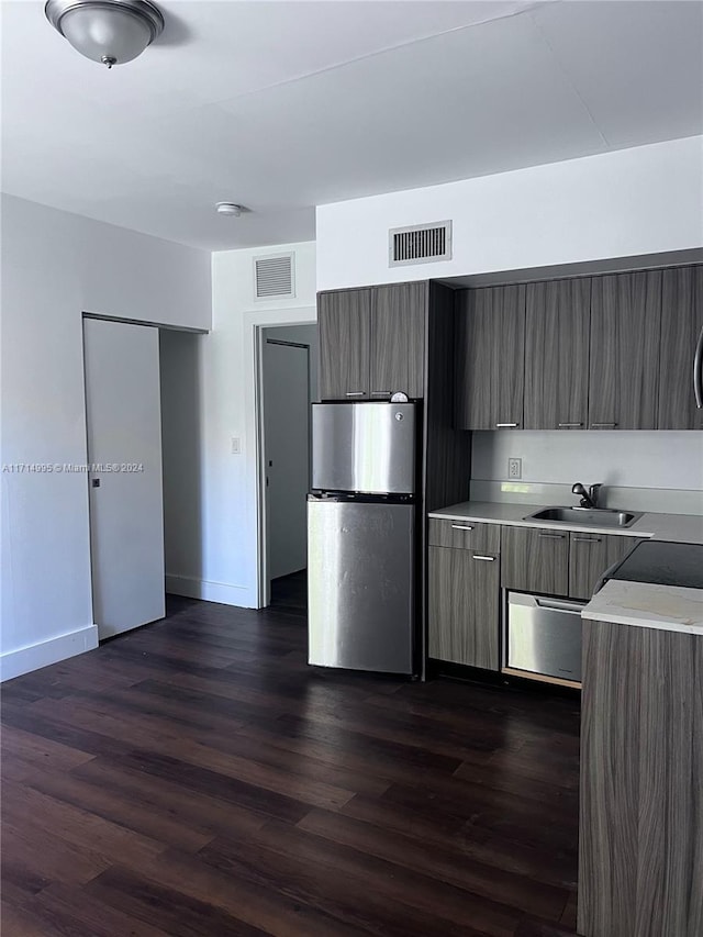 kitchen with dark hardwood / wood-style floors, stainless steel fridge, and sink