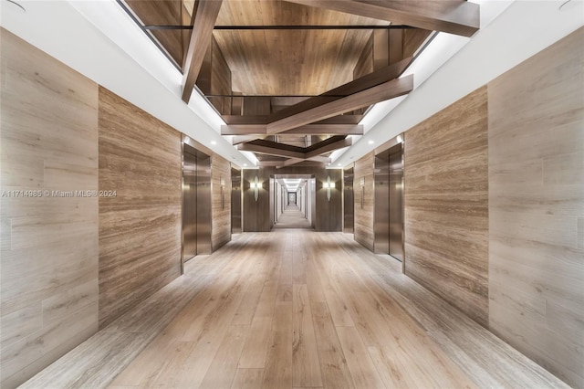 hallway featuring a high ceiling, elevator, and light hardwood / wood-style flooring