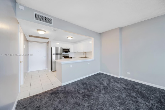 kitchen featuring sink, stainless steel appliances, kitchen peninsula, light colored carpet, and white cabinets