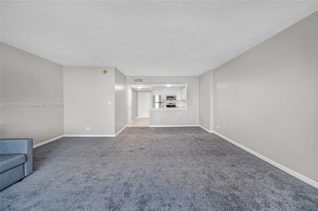 unfurnished living room featuring light carpet and a textured ceiling