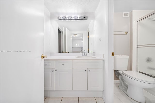 bathroom with tile patterned flooring, vanity, a textured ceiling, and walk in shower