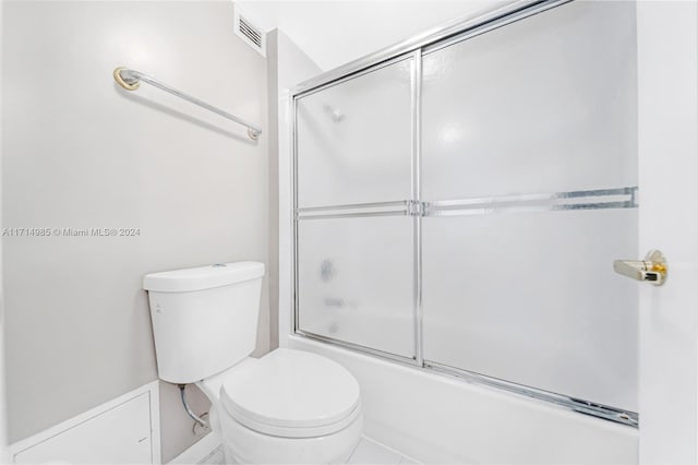 bathroom with toilet and shower / bath combination with glass door