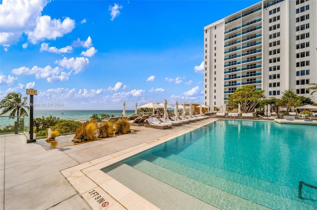 view of pool with a water view and a patio