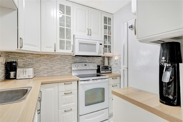 kitchen featuring tasteful backsplash, white cabinetry, sink, and white appliances