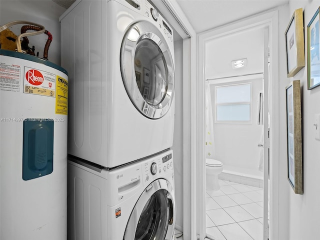 clothes washing area featuring electric water heater, stacked washer and dryer, and light tile patterned floors