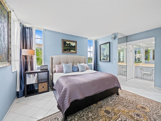 bedroom with tile patterned flooring, ensuite bath, and multiple windows