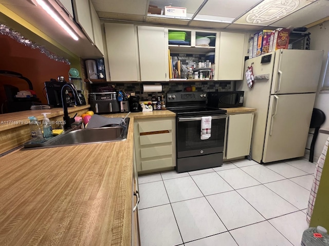 kitchen featuring a sink, decorative backsplash, black appliances, and light tile patterned floors