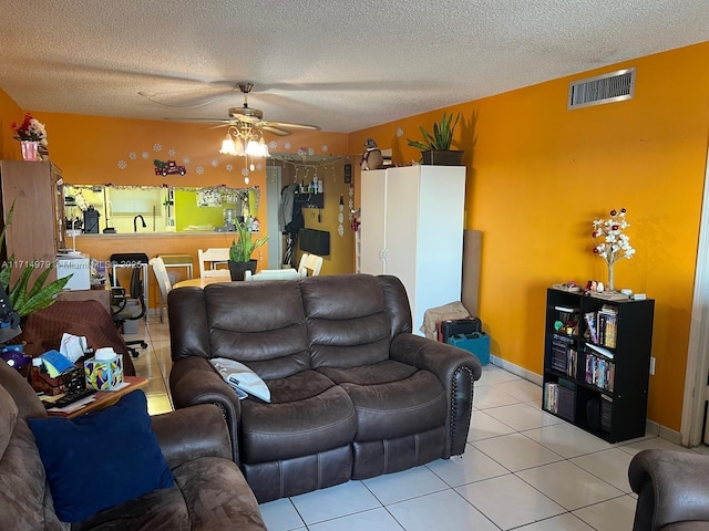 living room featuring visible vents, baseboards, ceiling fan, light tile patterned flooring, and a textured ceiling