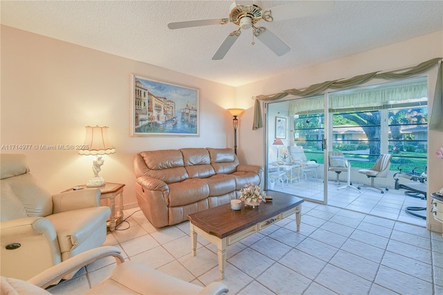 living room featuring ceiling fan, light tile patterned floors, and a textured ceiling