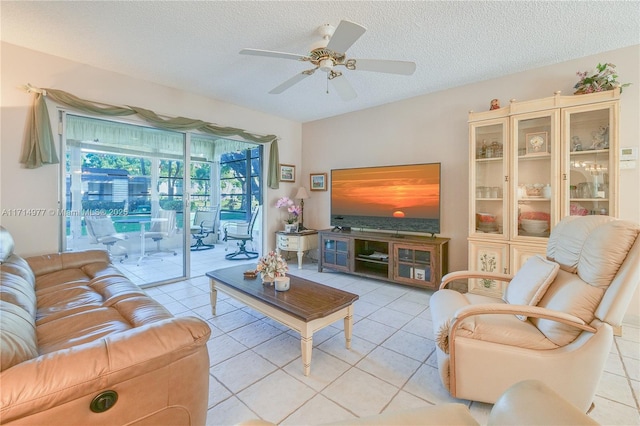 living room with ceiling fan, light tile patterned flooring, and a textured ceiling