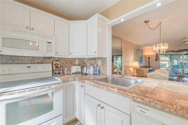 kitchen with white appliances, backsplash, sink, a notable chandelier, and white cabinetry