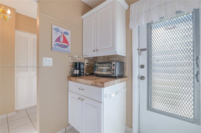 kitchen featuring backsplash, white cabinets, and light tile patterned floors