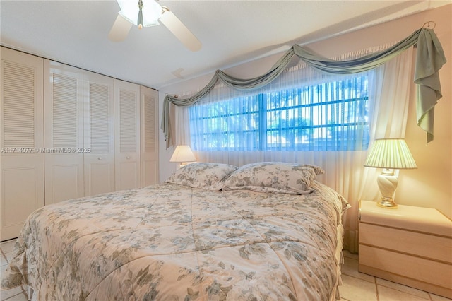 tiled bedroom with ceiling fan and a closet