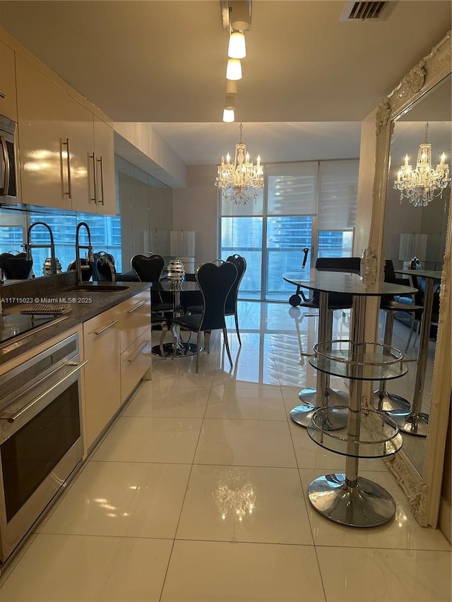 kitchen with sink, hanging light fixtures, stainless steel appliances, tasteful backsplash, and a chandelier