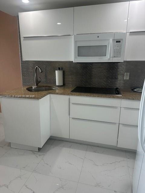 1250 S Miami Ave Unit 2013, Miami, FL 33130 - kitchen with white microwave, black electric stovetop, light marble finish flooring, white cabinetry, and dark stone counters