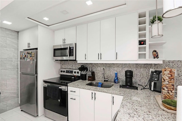 kitchen with decorative backsplash, light stone counters, stainless steel appliances, sink, and white cabinetry