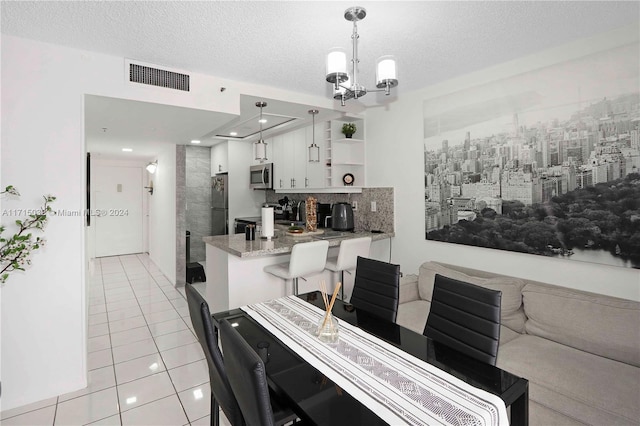 tiled dining space with a textured ceiling and an inviting chandelier