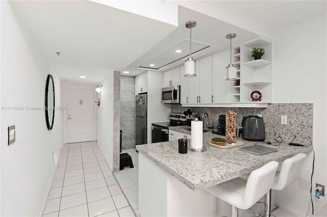 kitchen with white cabinets, appliances with stainless steel finishes, kitchen peninsula, and pendant lighting