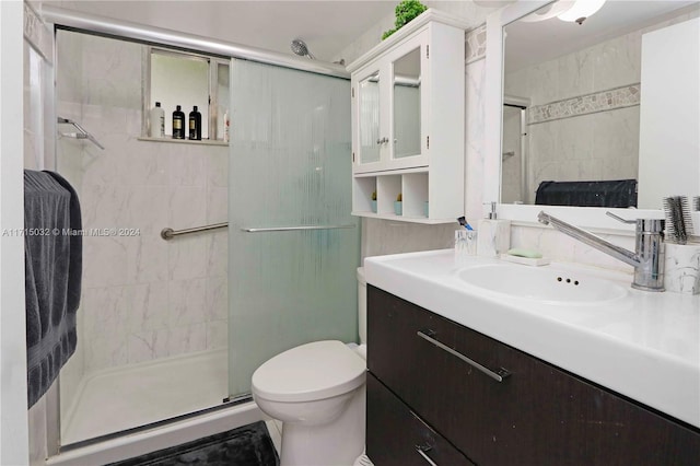 bathroom with a shower with door, vanity, and toilet